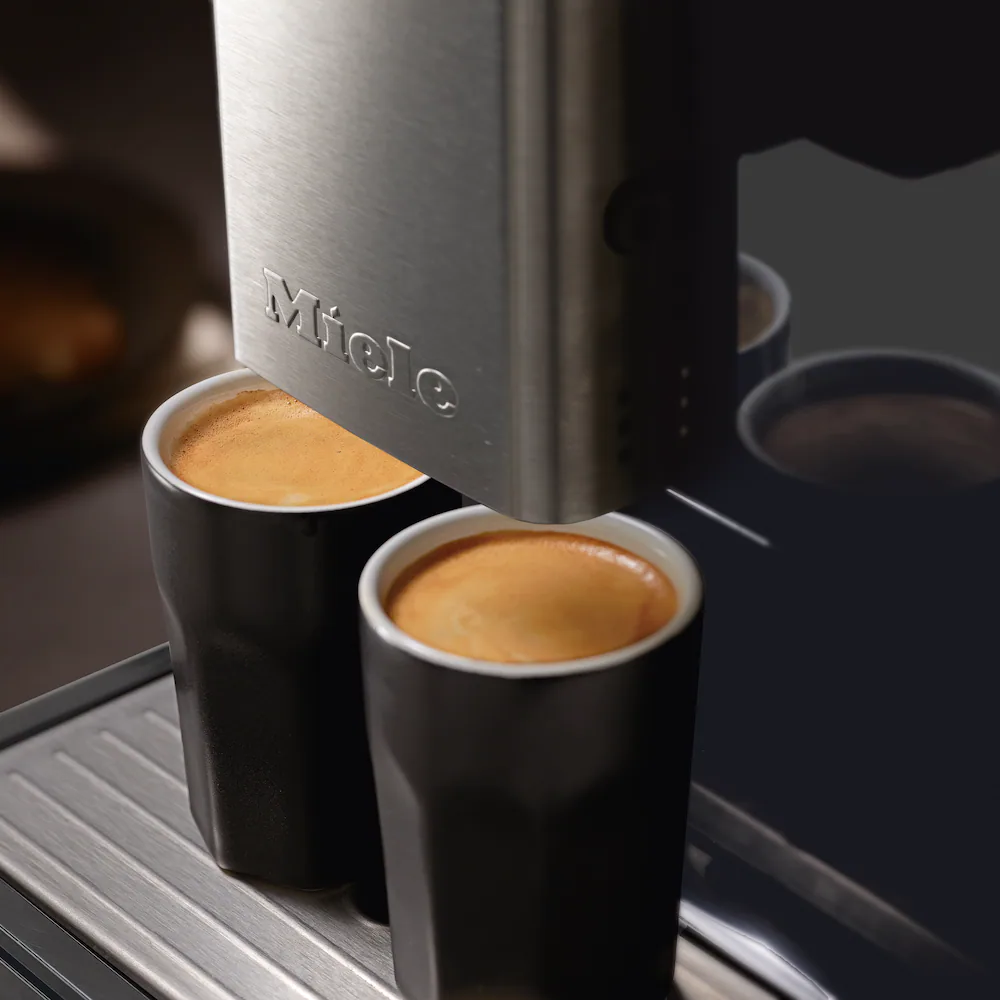 Miele close-up foto van twee vers gemaakte warme dranken uit een koffiemachine